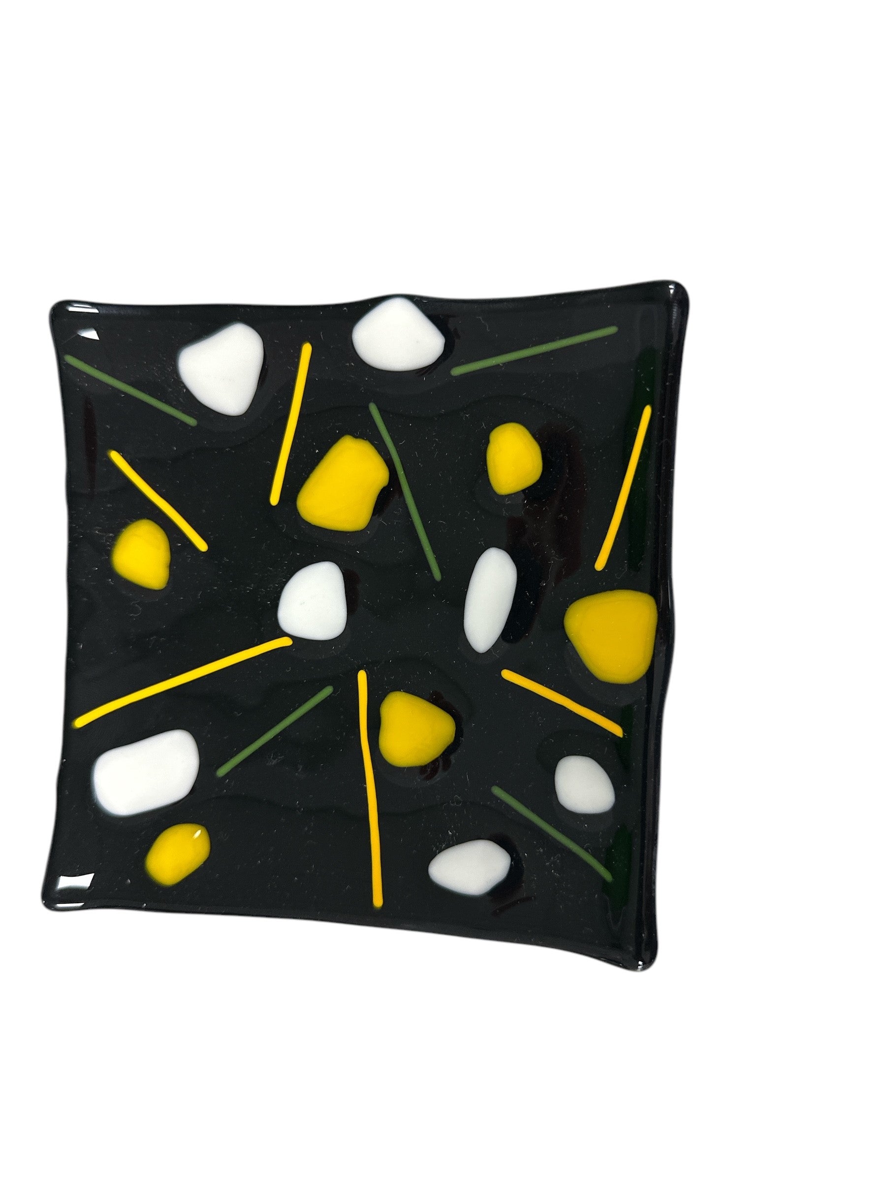 Black glass wavy plate with colorful decorations of yellow and white.