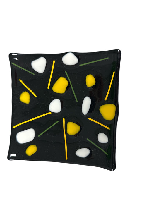 Black glass wavy plate with colorful decorations of yellow and white.