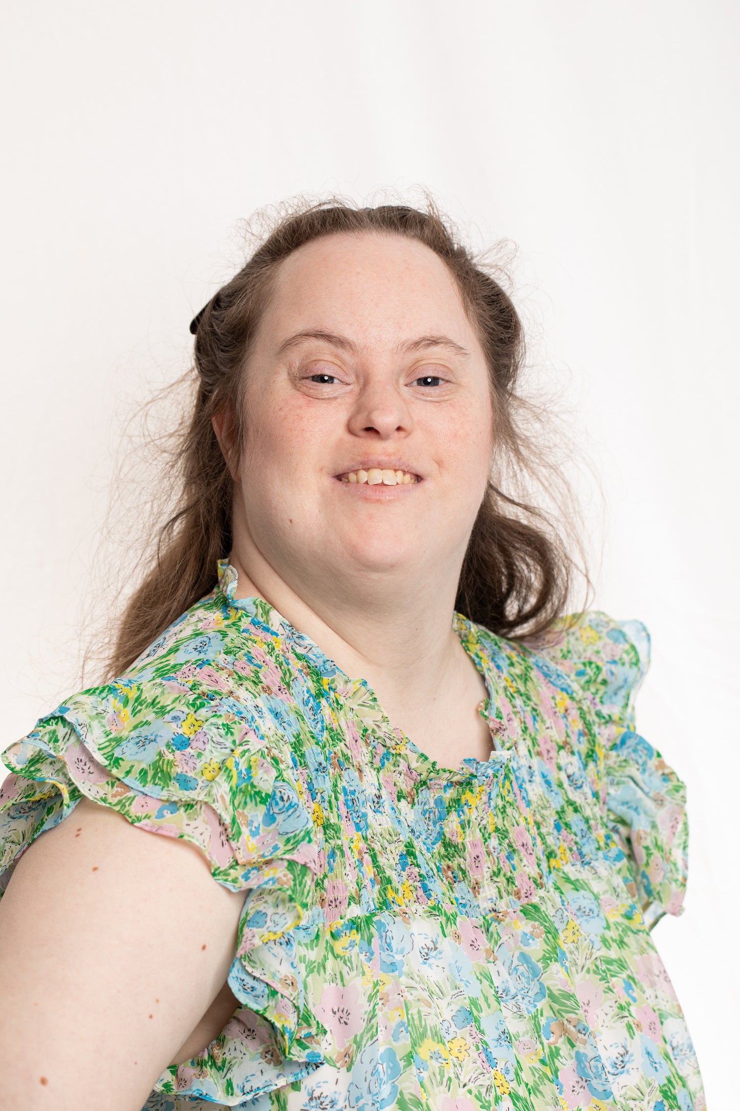 Young lady wearing floral shirt, hair pulled back from face, smiling