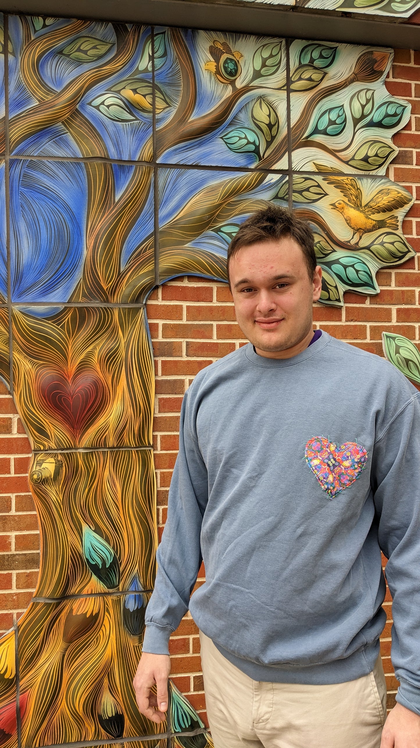 Male wearing a sweatshirt w/ Heart patch made of original artwork.