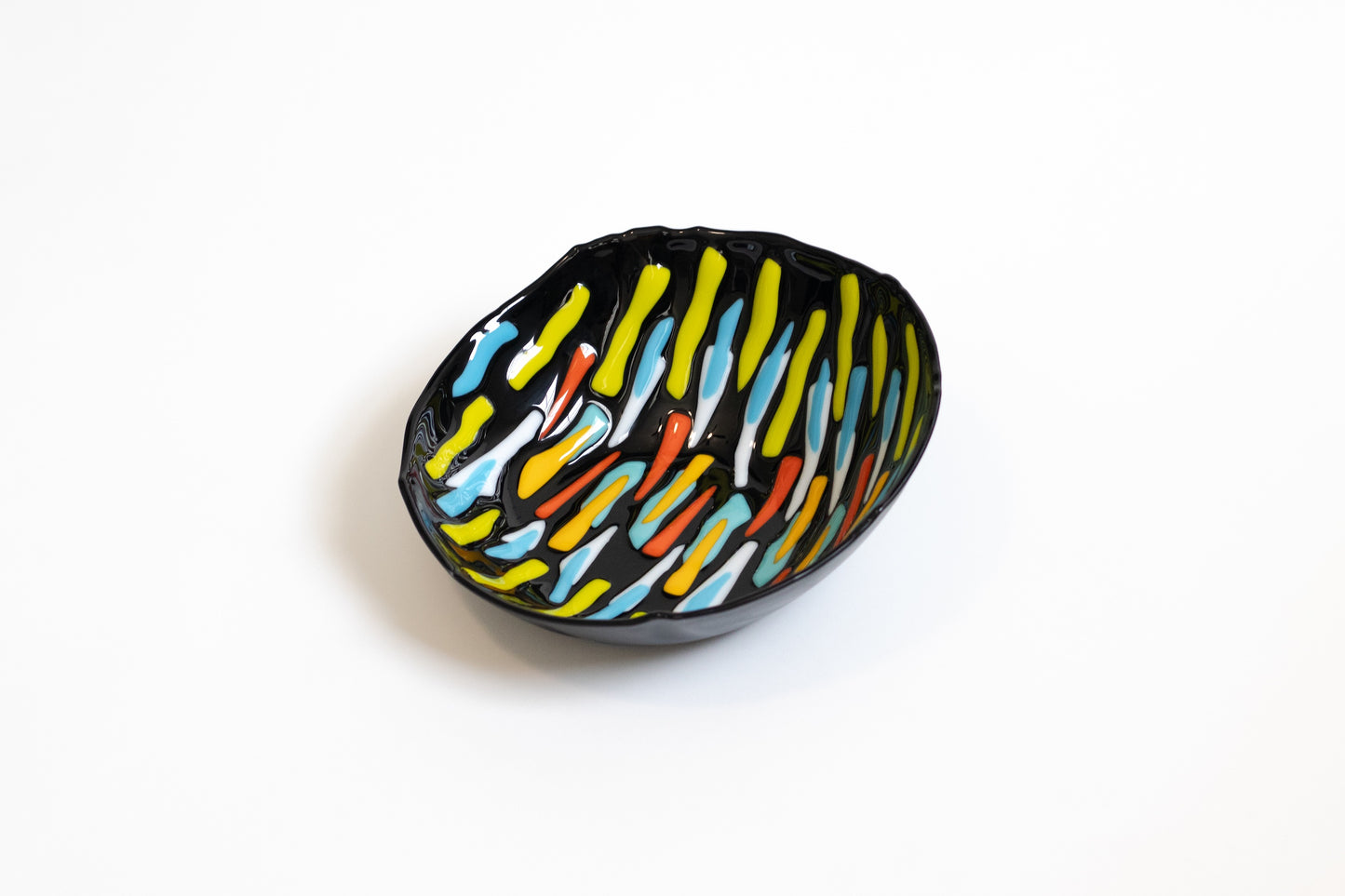 black bowl with lines of green, yellow, white, orange, and blue