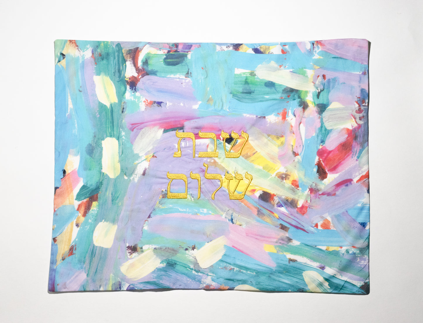 challah cover that is of an abstract pattern with pastel colors embroidered with shabbat shalom in hebrew