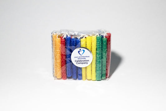 Package of rainbow hand-rolled beeswax candles in purple, red, orange, blue, green, and electric yellow