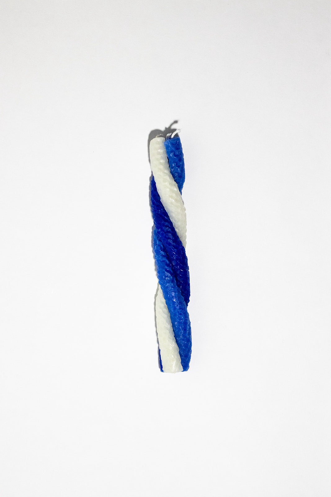 Long candle made up of three candles twisted together. The candle colors are white, navy and electric blue.