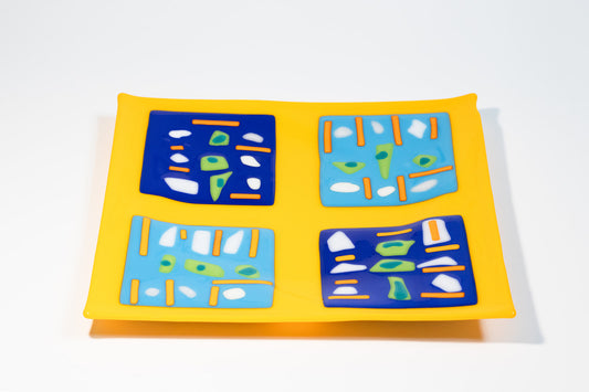 yellow square glass plate with four blue squares with orange lines, white and green dots inside