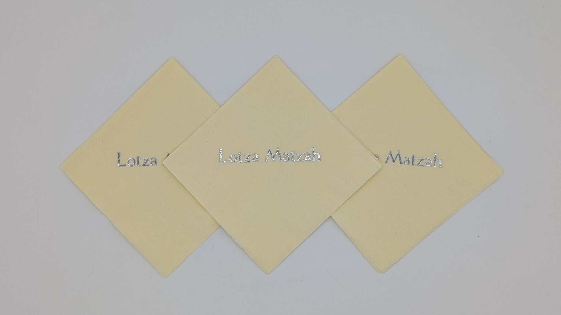 grouping of 3 cream napkins that say lots of matzah