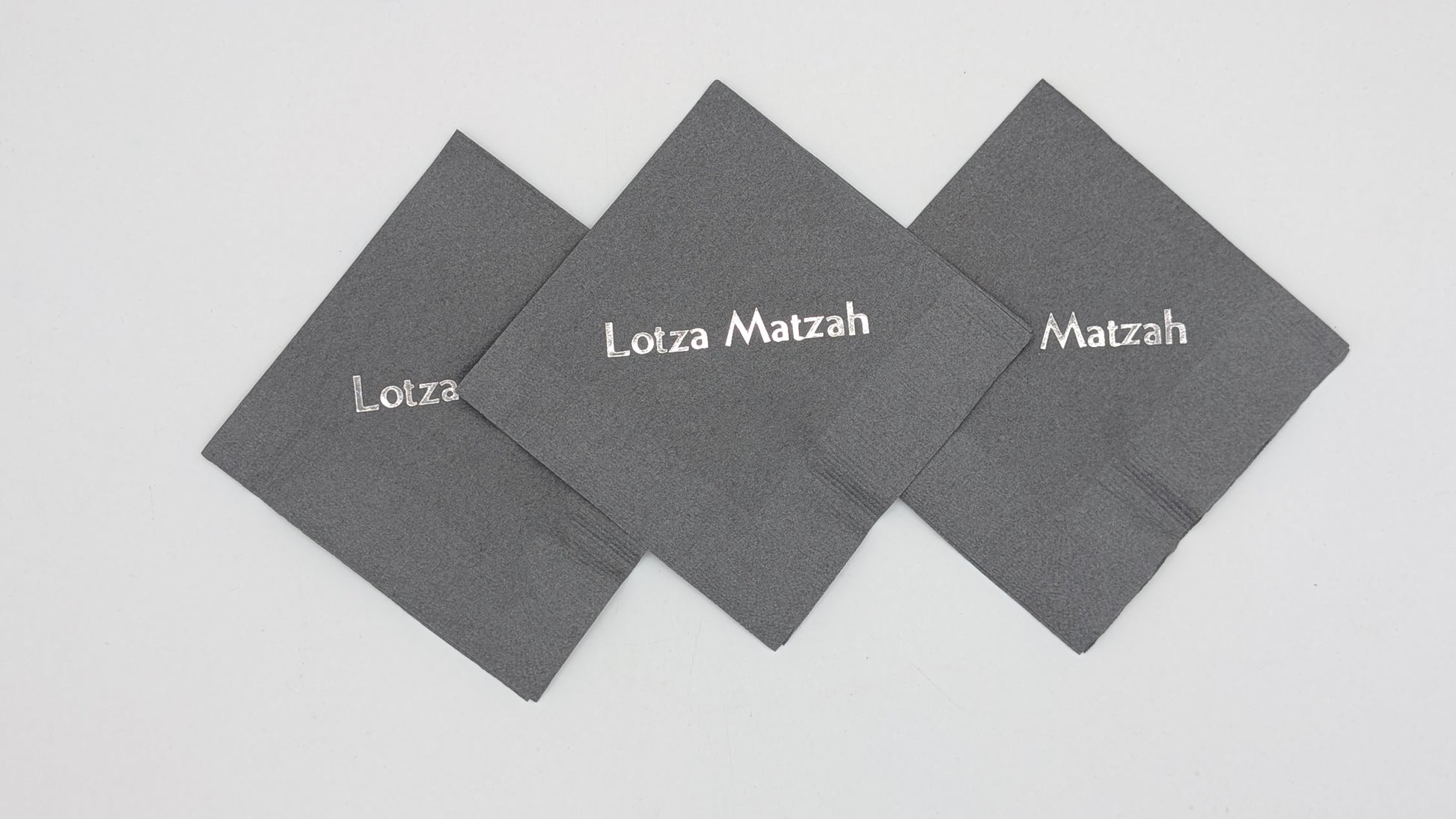 grouping of 3 gray napkins that say lots of matzah