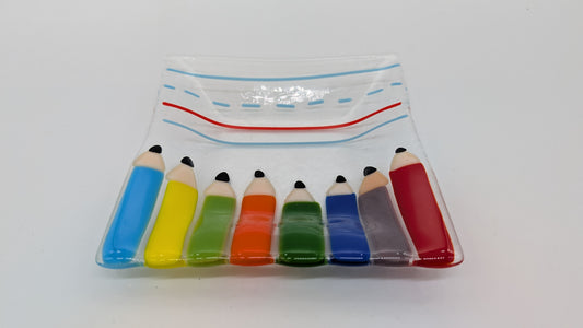 glass plate with pencils on the bottom and ruled paper at the top of the plate