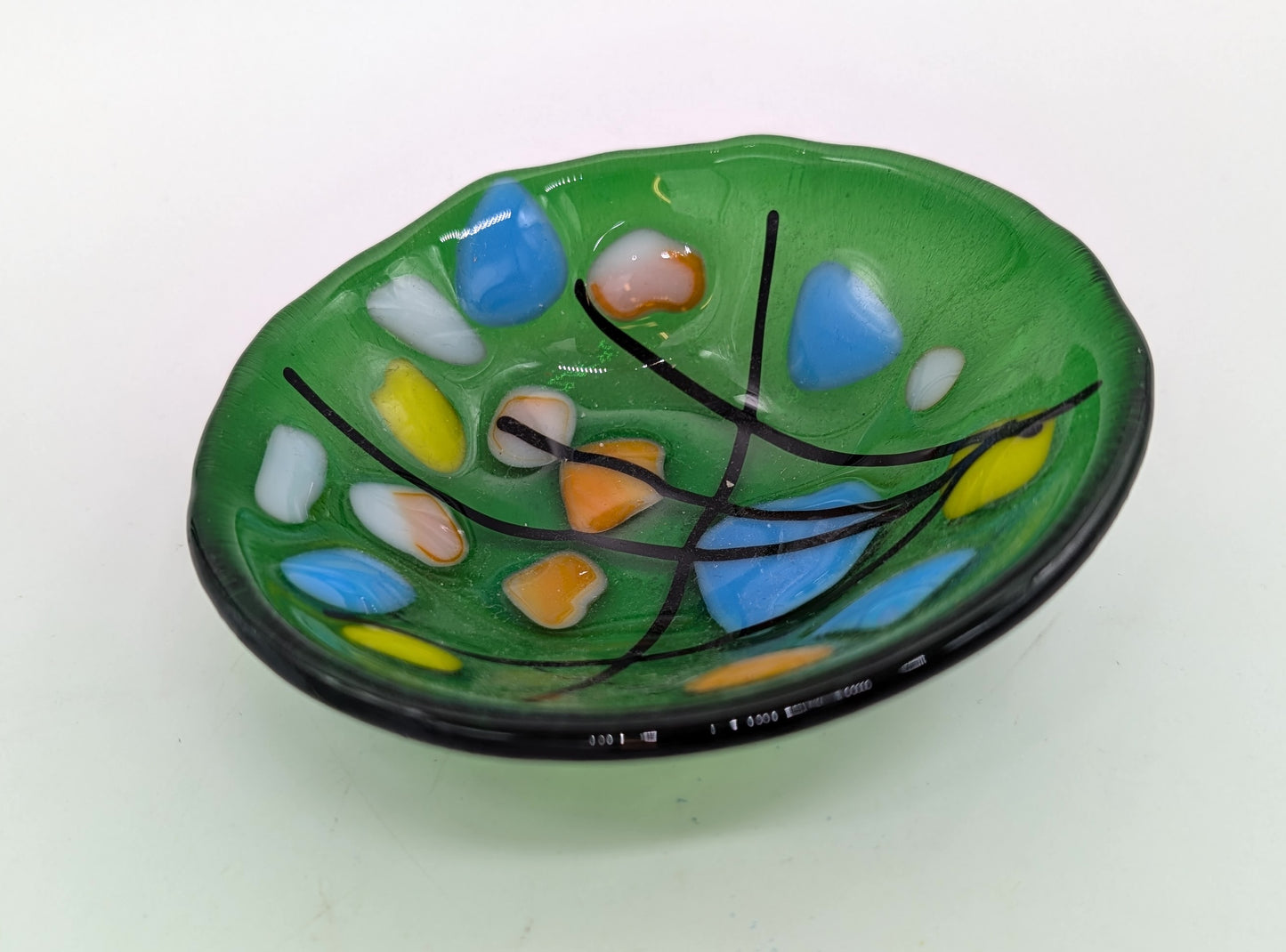green glass trinket bowl with black lines and blue and orange dots