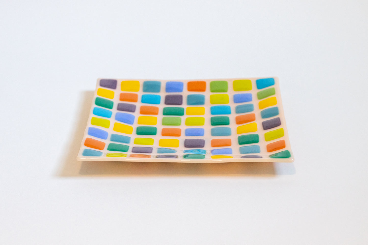 Pink fused glass plate with colorful squares pattern