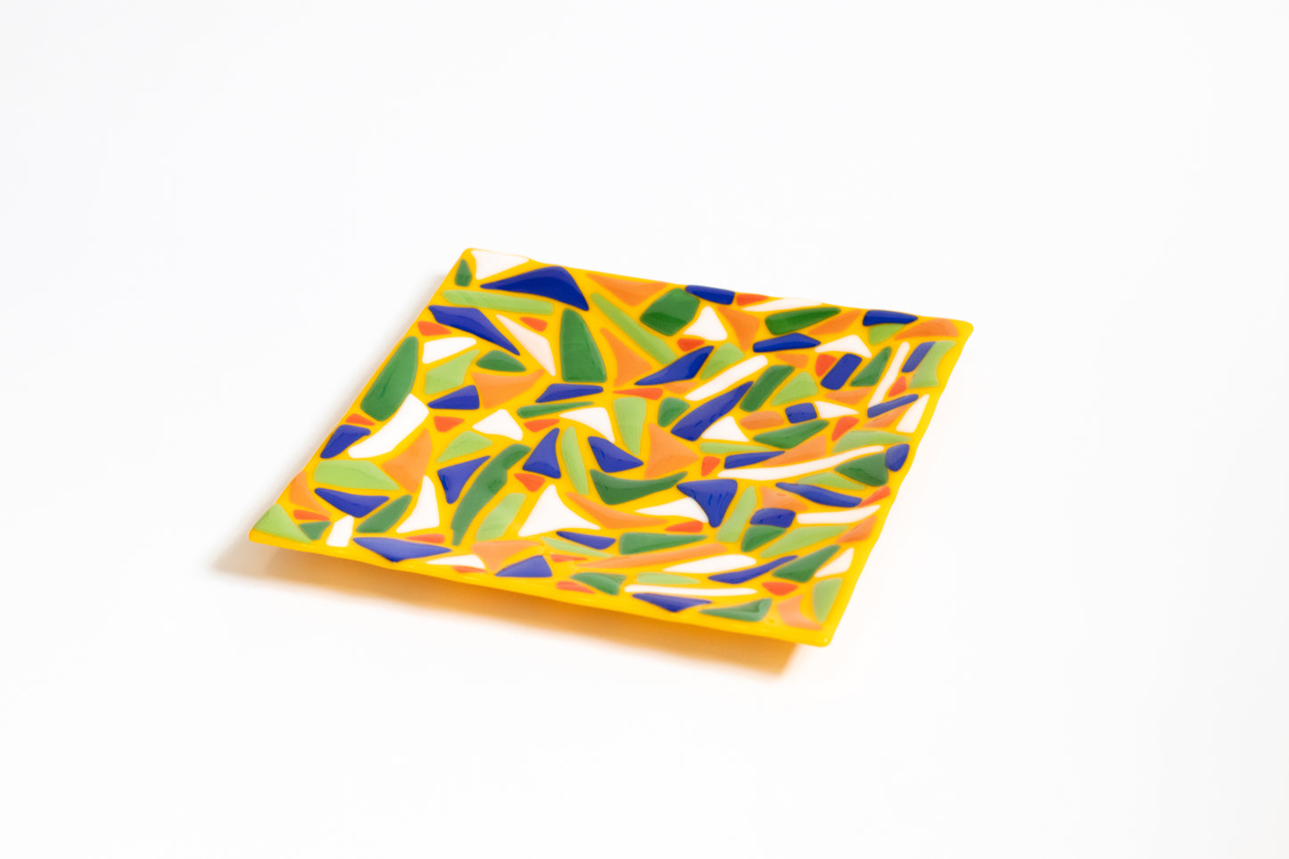 Yellow fused glass plate with white, blue, green, and orange designs