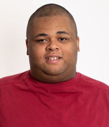 Smiling young man with a shaved head wearing a red shirt.