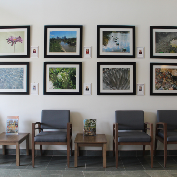 eight celebration company artist photographs displayed on the wall of a waiting room with three chairs and two tables below them.