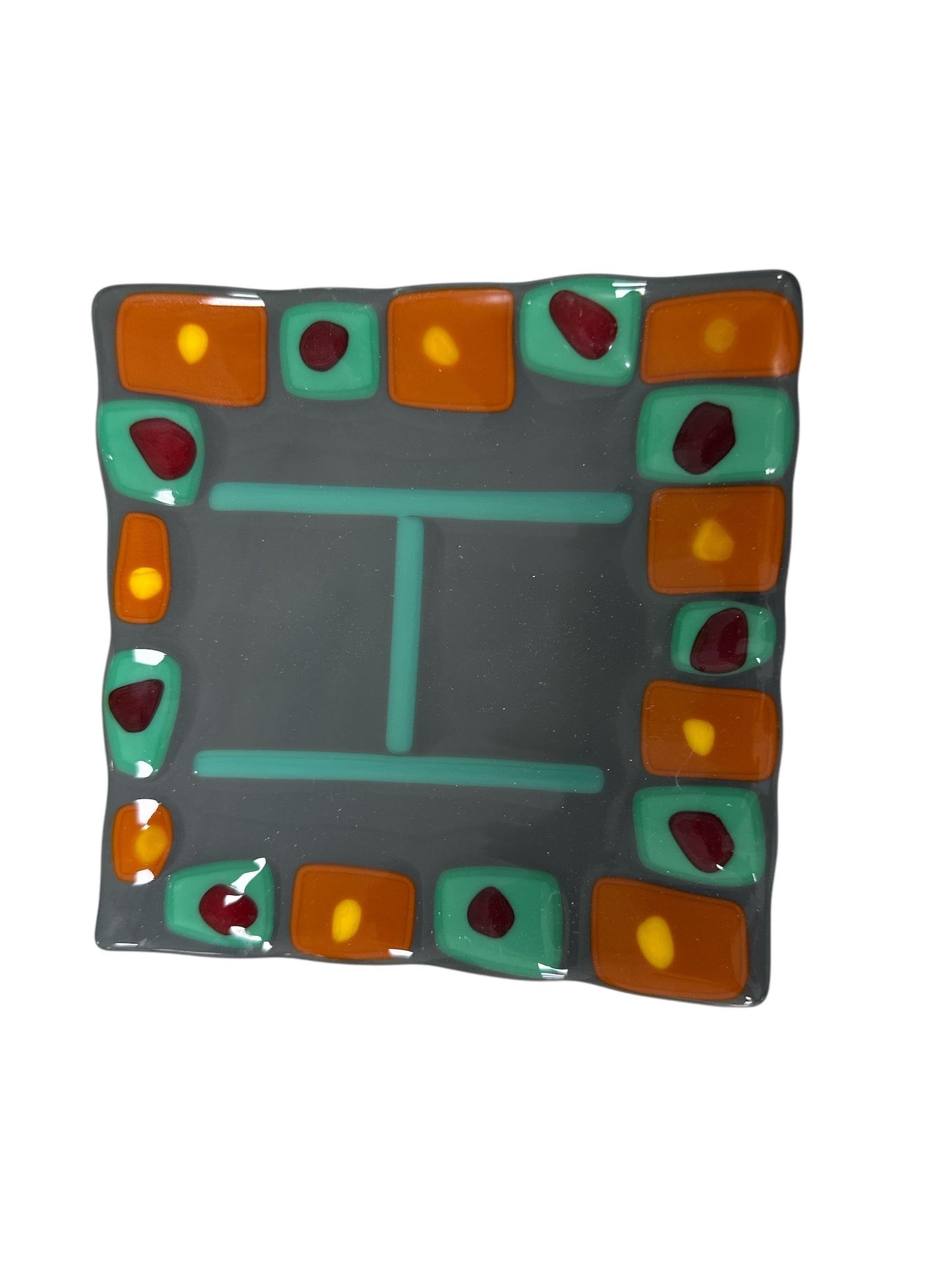 Wavy tray with a gray background, letter H in the middle. Brown, yellow and orange dots around.