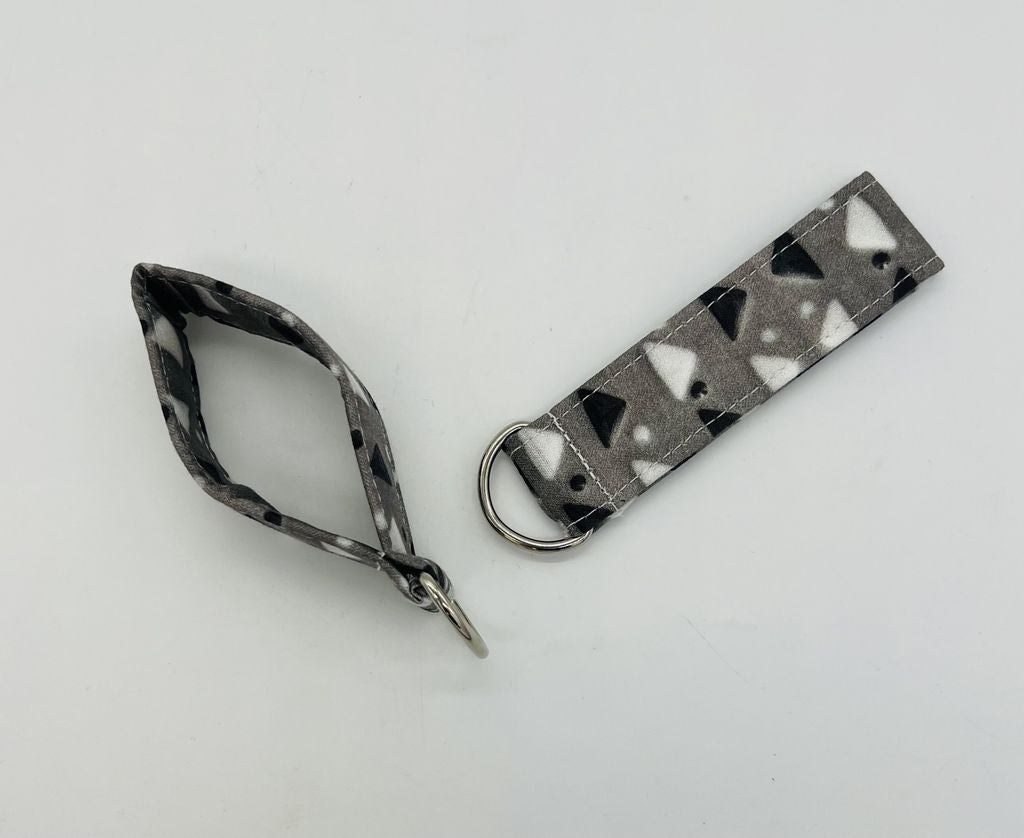 key chain of a Gray glass square plate with black and white alternating triangles and dots in between