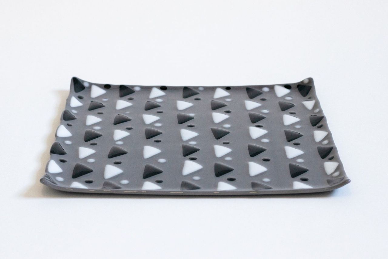 Gray glass square plate with black and white alternating triangles and dots in between