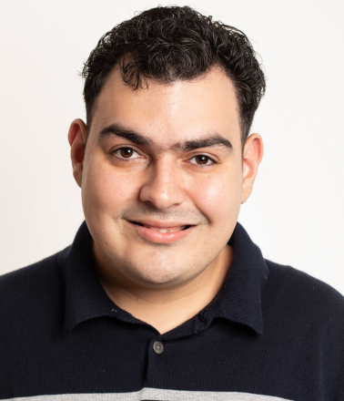 Smiling man with dark hair wearing a navy polo shirt.