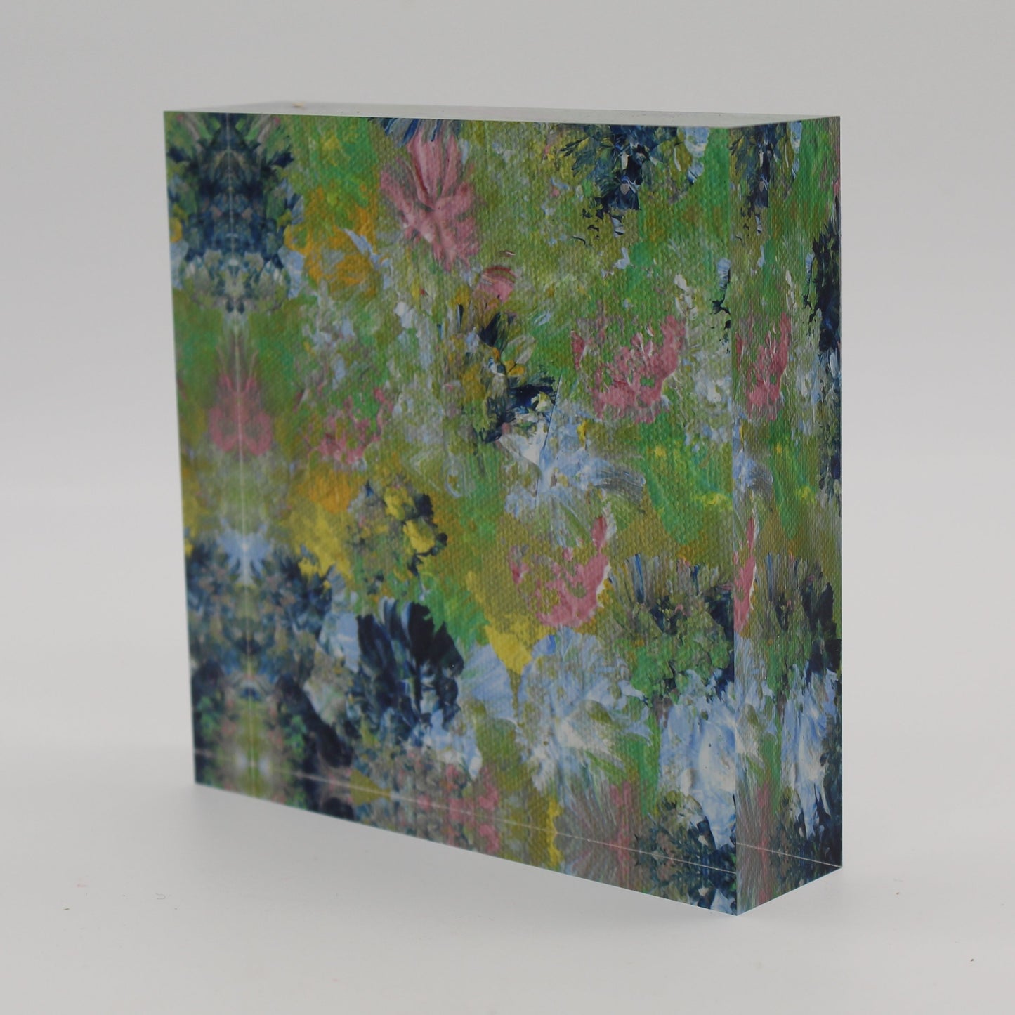 Tilted view of Acrylic block depicting spring flowers of pink, dark and light blue, green and yellow