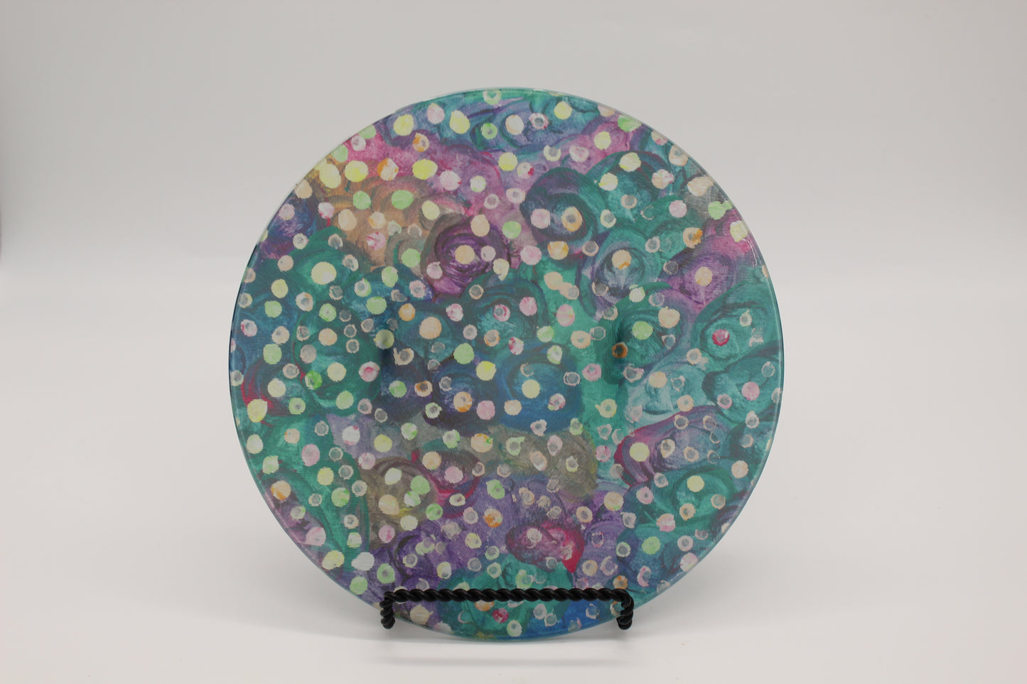 Glass cutting board with blue, green and purple swirl background with yellow, green and pink dots