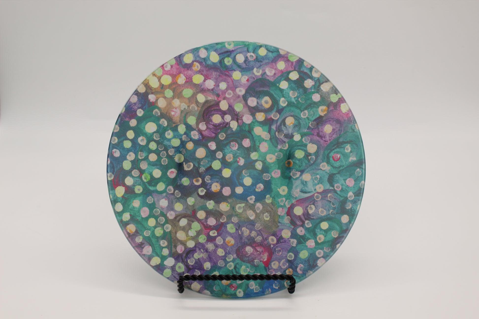 Glass cutting board with blue, green and purple swirl background with yellow, green and pink dots