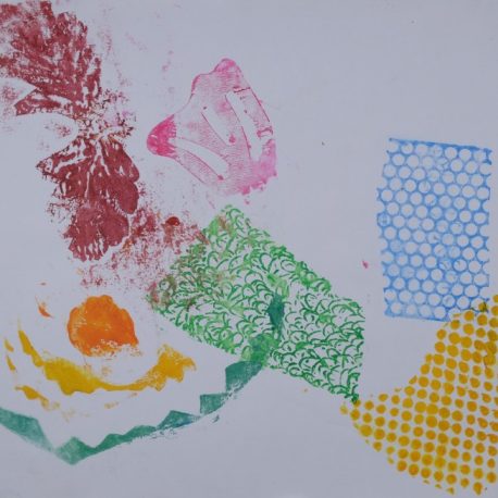 Ink on paper artwork with stamps of various colors and patterns. Green swirl, blue honeycomb, yellow dots, pink flower, orange dot