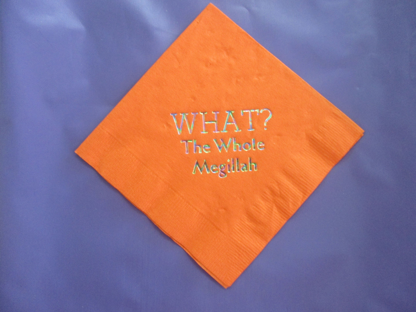 Orange cocktail napkins with an iridescent What? The Whole Megillah slogan