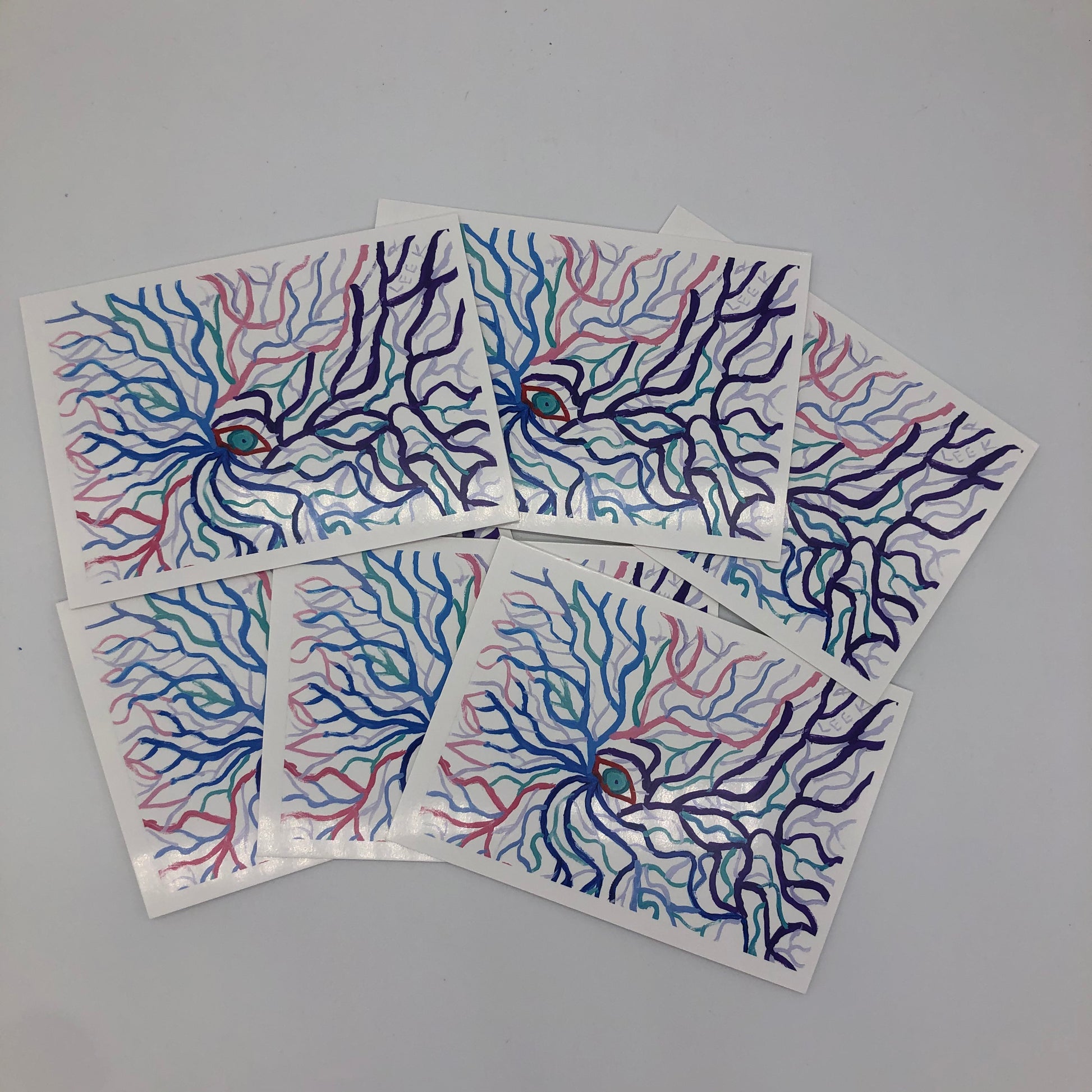 Six of the graphic card shown.  The card is a printed graphic card with a small blue-green eye in the middle.  The eye is outlined in red and radiating from eye are branch like lines in blues, red, pink, greens and purple.