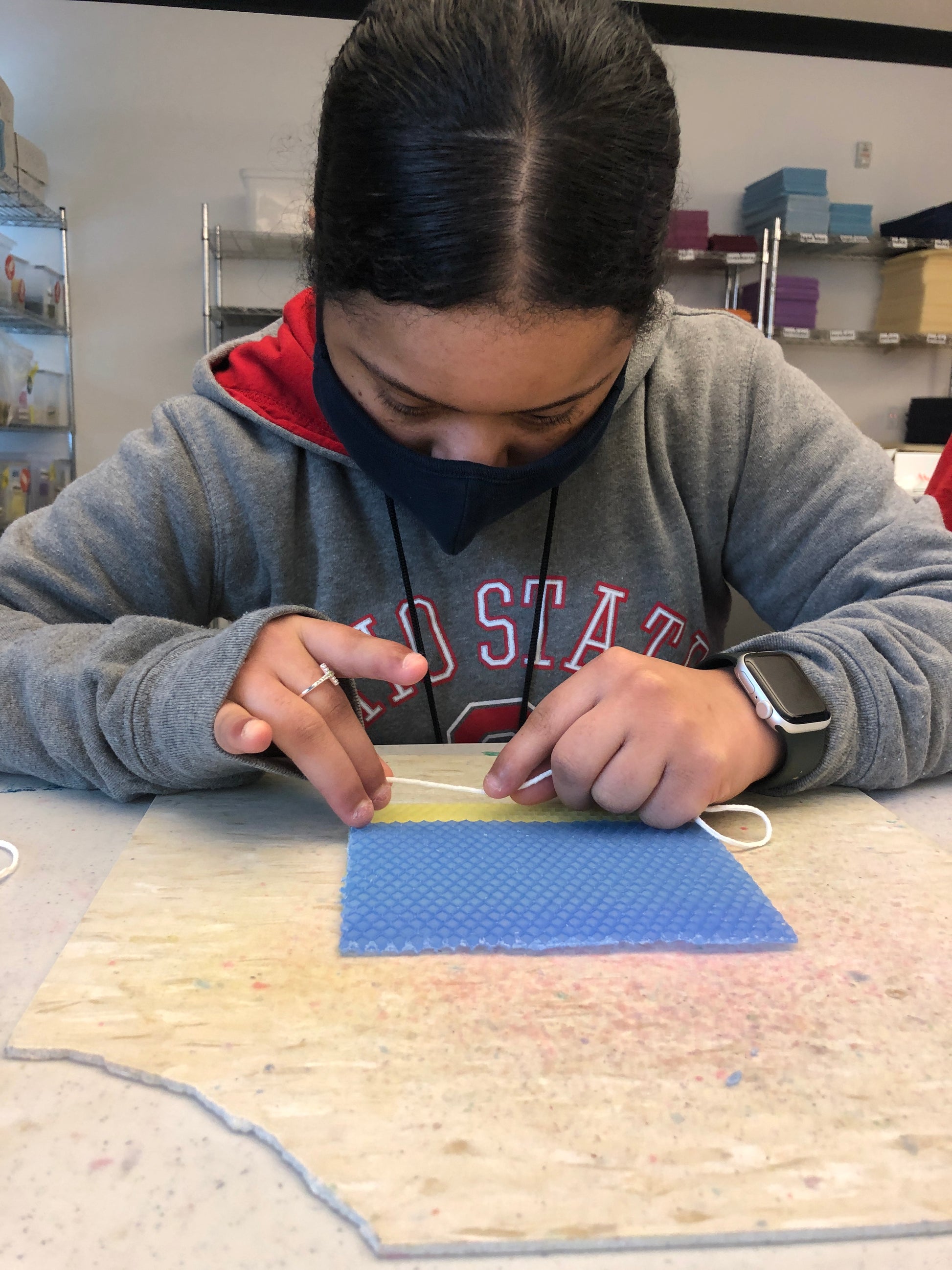 picture of young lady rolling candles that are yellow and blue