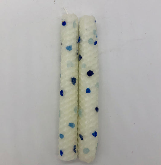 Two white shabbat candles with dots of color in four shades of blue.