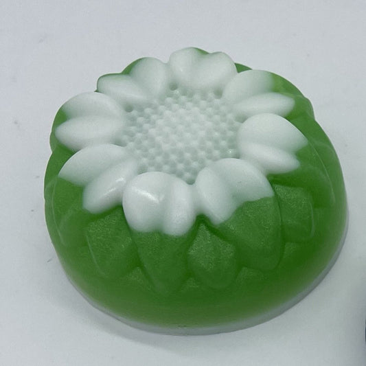 Round floral soap with green base and white on top.