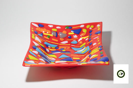 red glass bowl with yellow lines and accents of blue and white