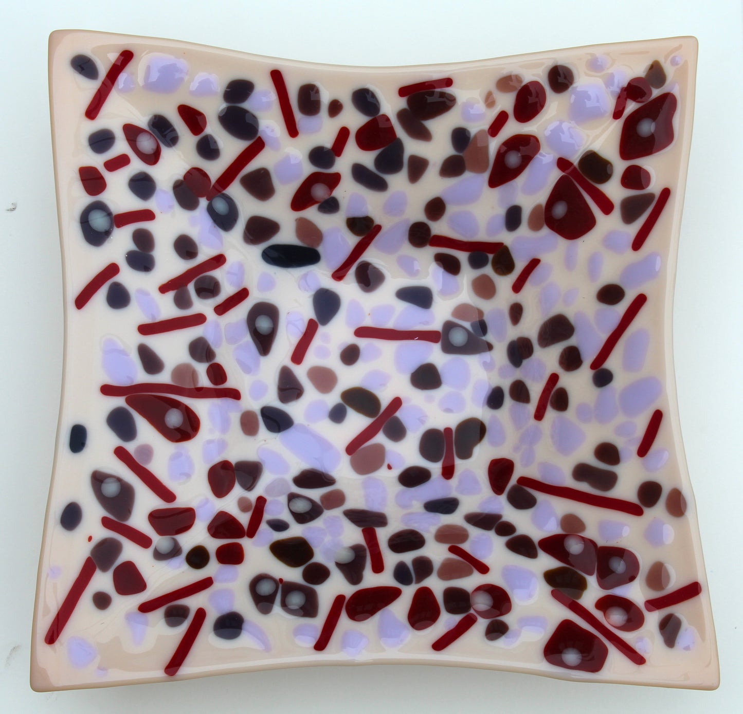 tan square bowl with spots of purples and red lines in between