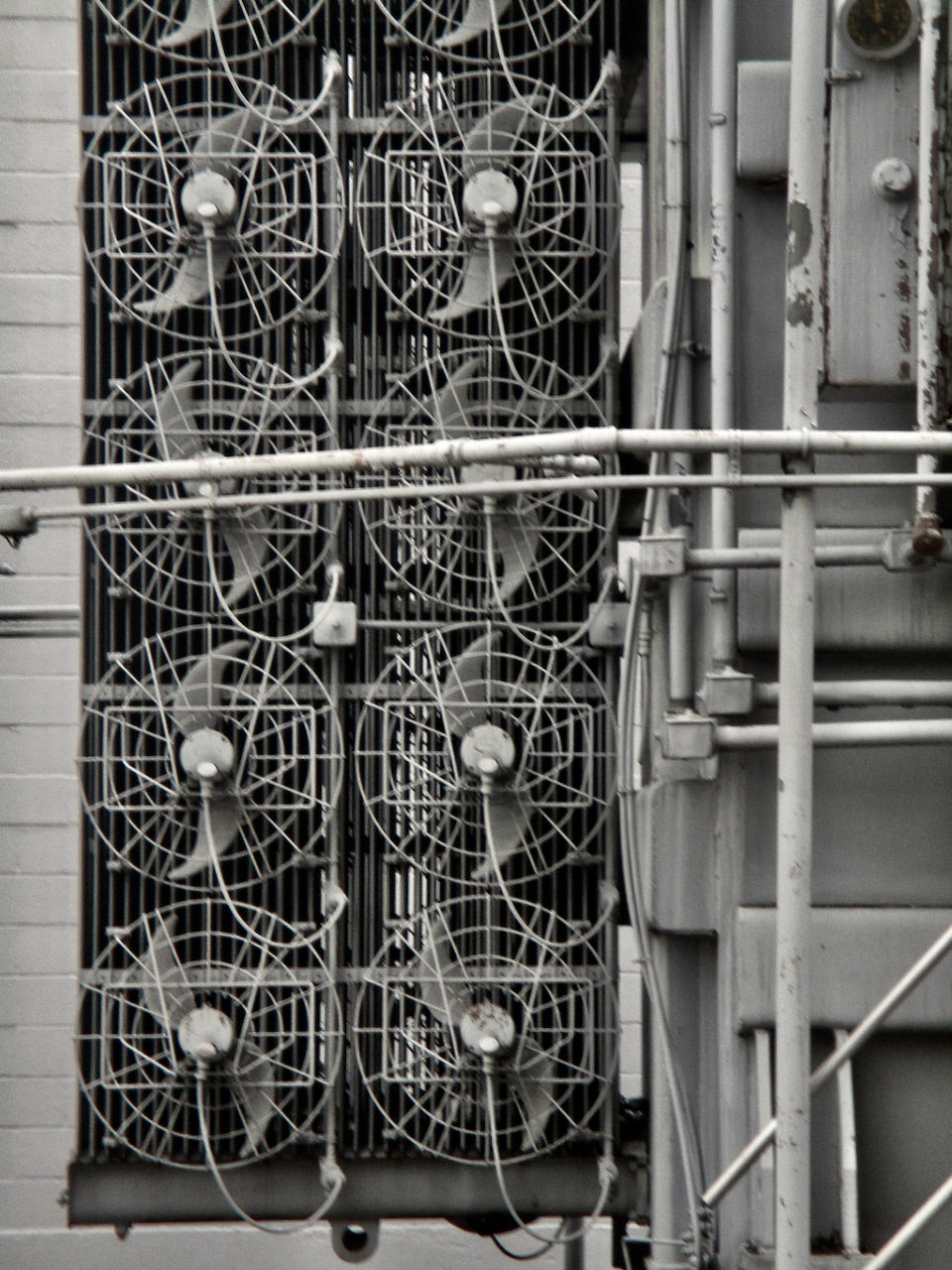 This is a black and white photo of 8 fans in an industrial setting