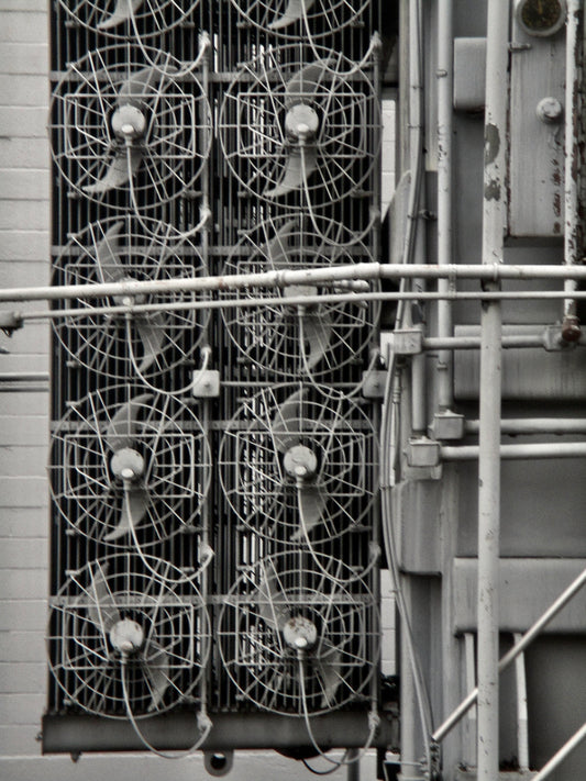 This is a black and white photo of 8 fans in an industrial setting