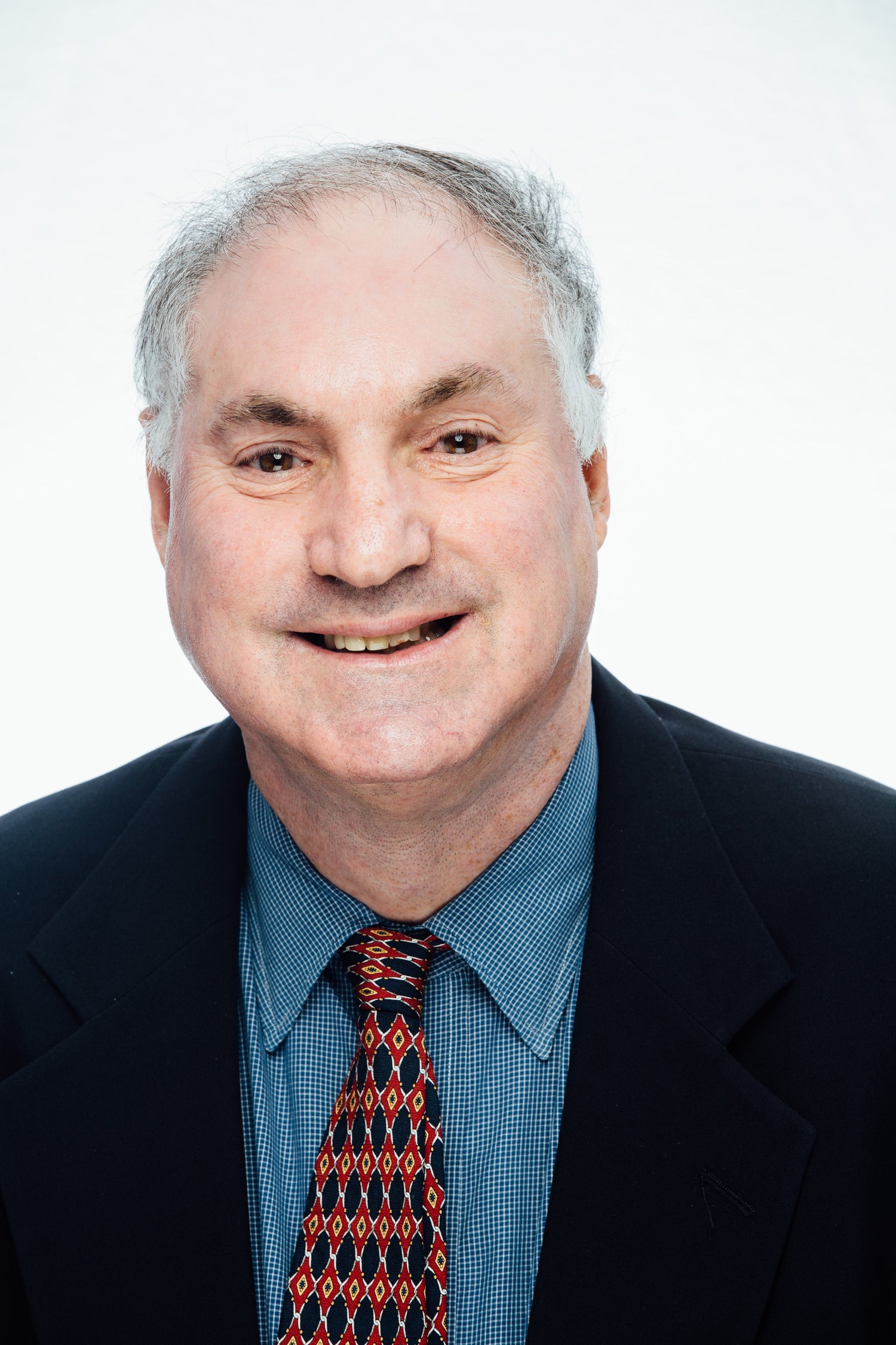 Artist smiling wearing a suit with a red patterned tie