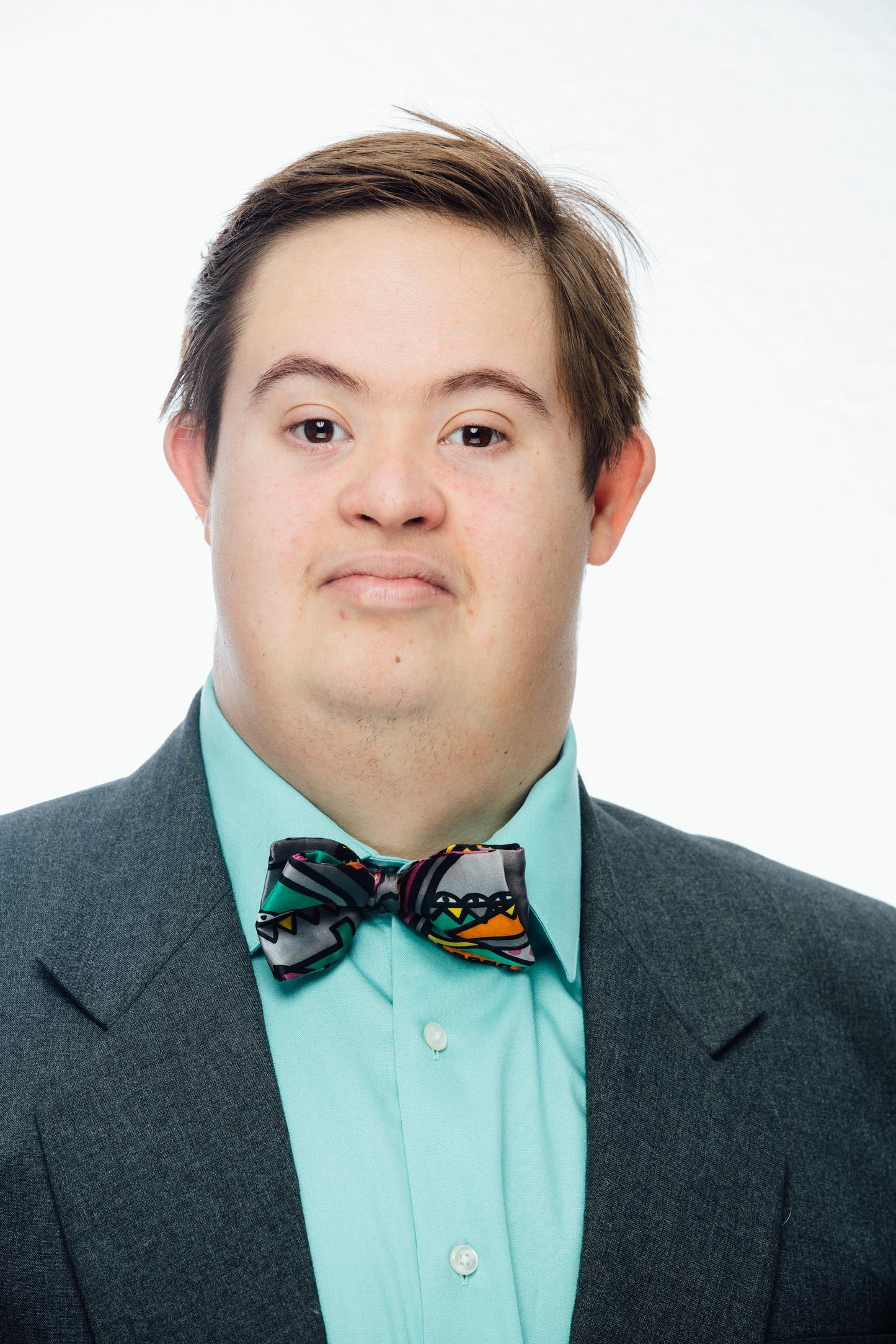 Smiling young man wearing gray suit, turquoise shirt and bowtie
