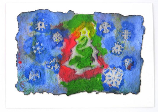 Printed Christmas card from photo of handmade paper with Christmas tree in the center in red and green. THe background is in blue and white with snowflakes.