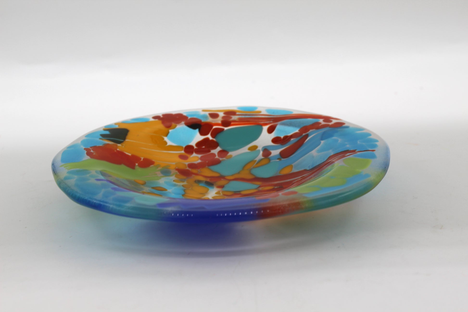 Glass bowl with sections of mostly blues with spaces of orange, red, and green