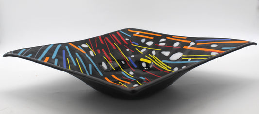 This is a black square glass art with multicolored lines in red, yellow, blue, and orange. It has white dots overlaying it