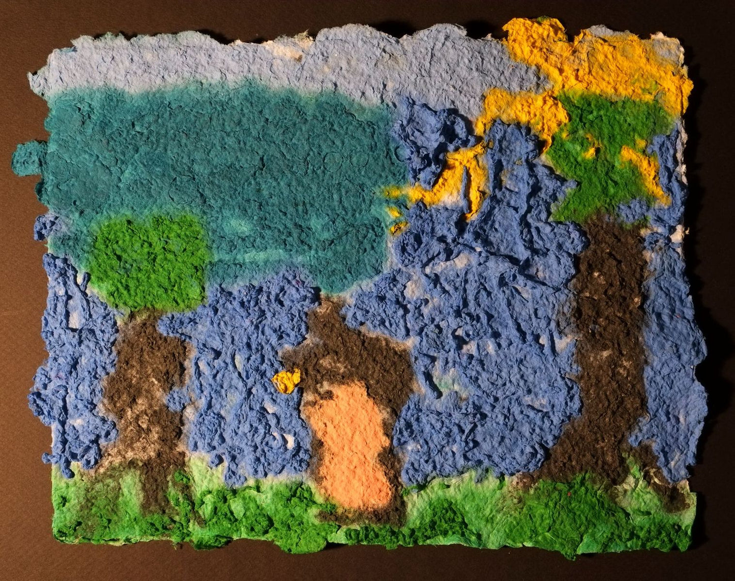 Pigment on recycled paper artwork depicting brown and green trees against blue sky with green grass and yellow sun