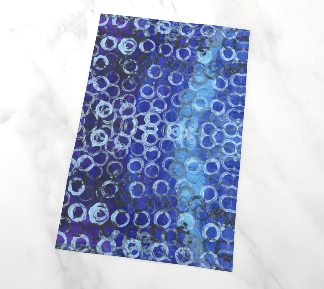 tea towel with a background of varying shades of blue, with the darker hues dominating, are dozens of rings; most are white, but about a tenth of them are black