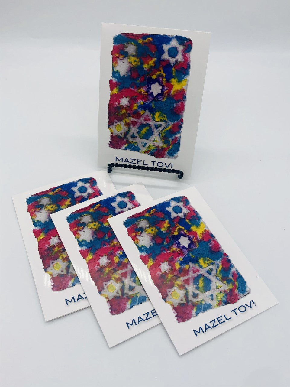 Pack of Graphic greeting cards with blue, red and yellow Jewish stars with Mazel Tov at the bottom