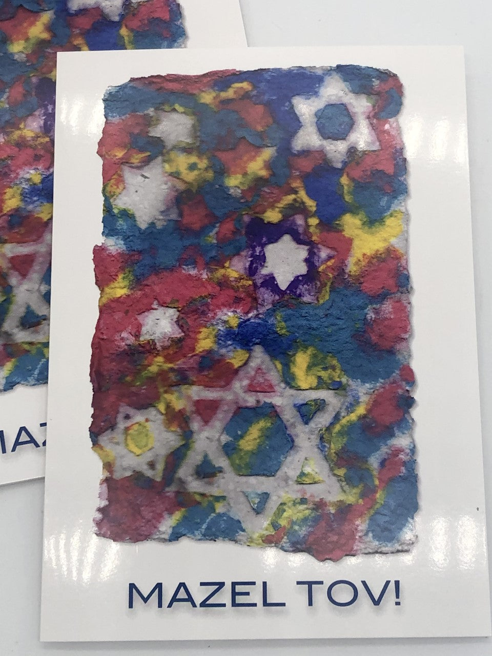 Graphic greeting card with blue, red and yellow Jewish stars with Mazel Tov at the bottom