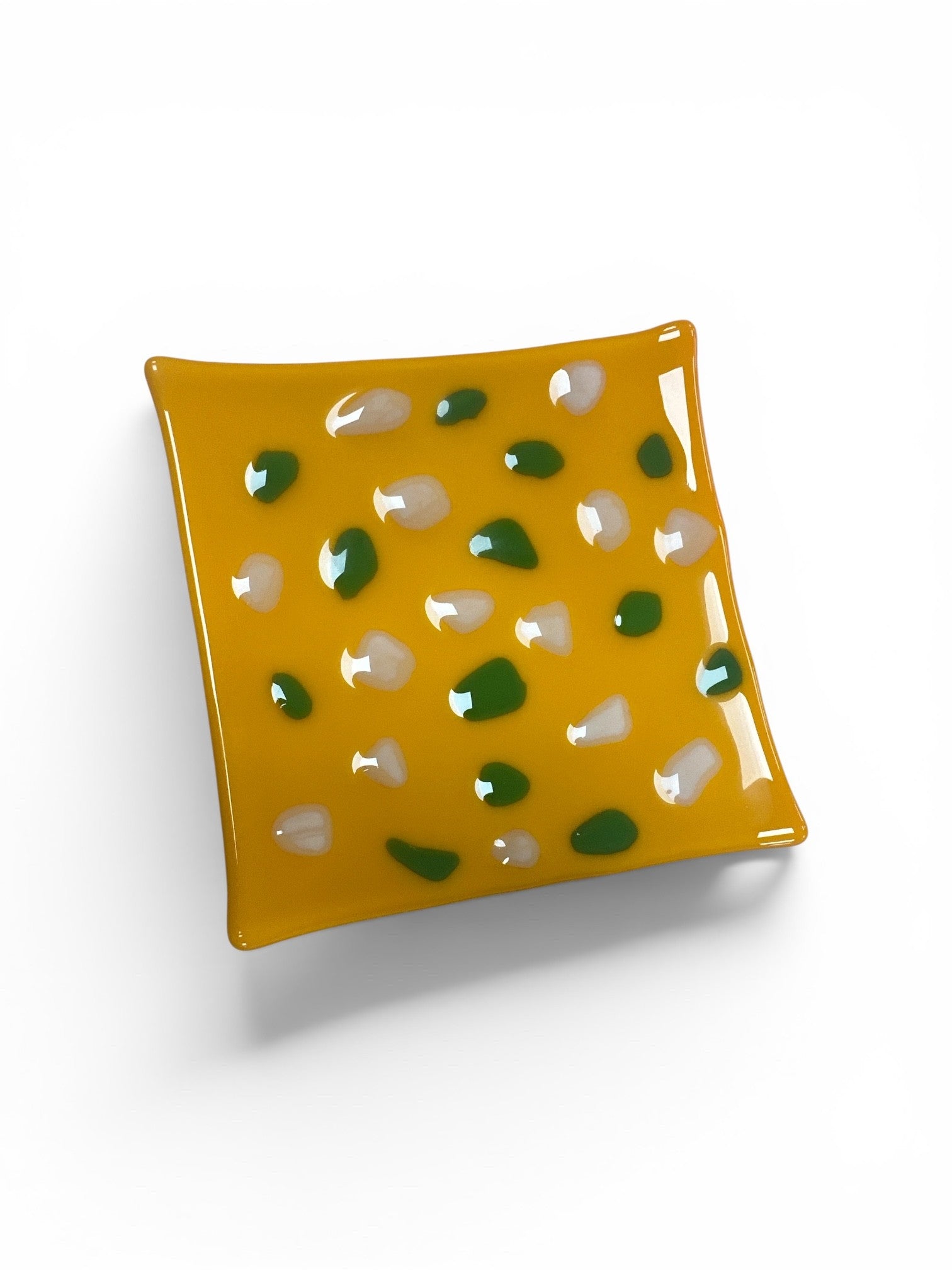 This is a square, vibrant yellow fused-glass decorative dish dotted with a playful, scattered pattern of small white and forest green glass accent pieces.