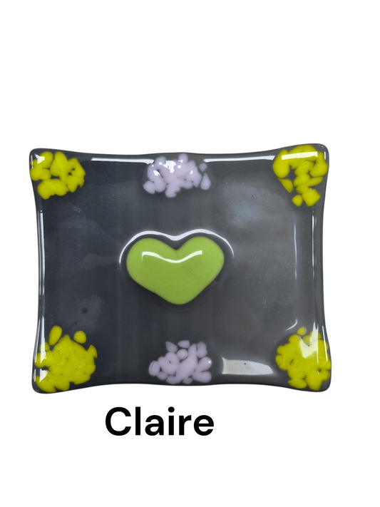 Handcrafted fused glass art tray, it showcases a bright green heart in the middle of the tray.
Medium: Fused Glass
Size: 6" x 6"
Year: 2026