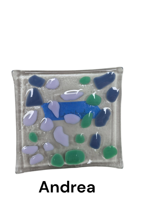 Handcrafted fused glass art tray, it features an abstract, mosaic-style arrangement of smooth, pebble-like glass pieces in cool tones of lavender, teal, and deep blue, set against a translucent, frosted glass base.

Medium: Fused Glass

Size: Approximately 6" x 6"

Year: 2026