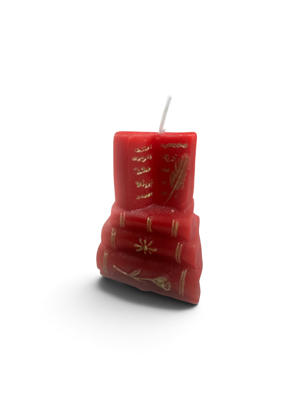 A miniature stack of red book candles with gold-detailed spines topped with an open book wick.