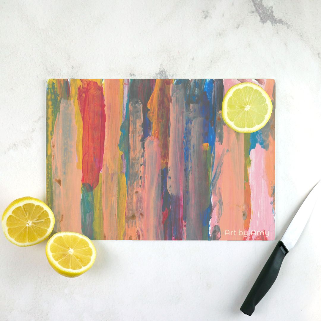 cutting board with Layers of vertical brushstrokes overlapping. In the center the background is a dark blue, to the left is yellow, and the right is pink. The top layer of brushstrokes are mostly a pale pink