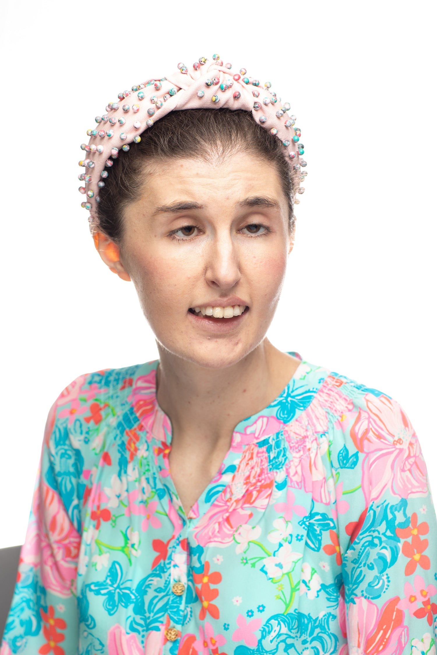 picture of young woman wearing a floral blouse and pink headband