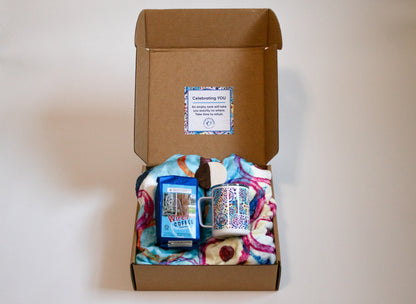 box with blanket, mug, coffee, and cookie